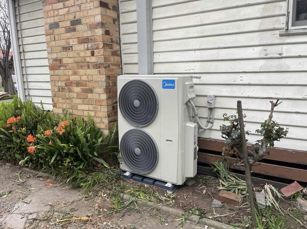 Midea outdoor unit beside weatherboard home